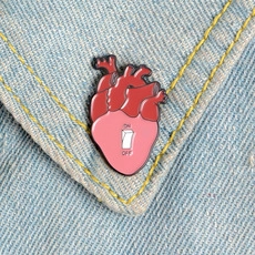 Close-up of an anatomical heart enamel pin with ON/OFF switch design on denim jacket