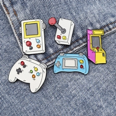 Detailed view of five colorful retro game console enamel pins on blue denim fabric