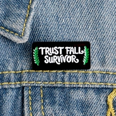 Detailed macro view of Trust Fall Survivor enamel pin on a classic denim jacket lapel