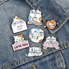 Detail of seven cute cat enamel pins showing emotional phrases on denim jacket