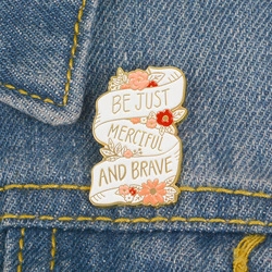 Détail d'une broche en forme de cœur avec message BE BRAVE sur tissu denim