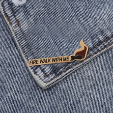 Close-up of Fire Walk With Me matchstick enamel pin on a blue denim jacket collar