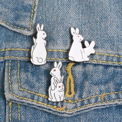 Détail de trois épingles lapin en acrylique blanc fixées sur un tissu en denim bleu