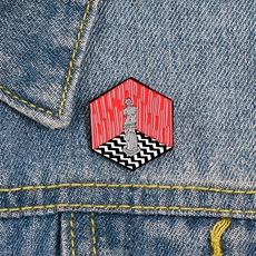 Detail of artistic enamel brooch with a statue and red curtain on denim fabric