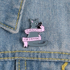 Detailed macro view of a grey cat enamel pin with feminism slogan on denim fabric