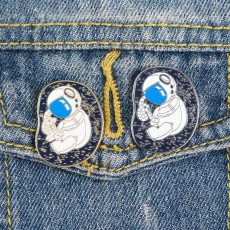 Close-up of cute astronaut enamel pins styled on a blue denim jacket pocket