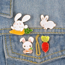 Détail de broches en émail de lapin blanc et de carotte sur un tissu en denim bleu