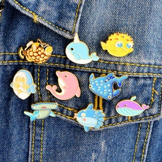 Detailed set of 8 colorful marine animal enamel pins on a denim jacket background