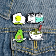 Detail of four creative food enamel pins on a denim jacket including sushi and avocado