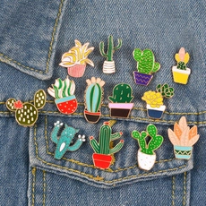 Close-up of thirteen colorful enamel cactus and succulent plant brooches on a denim jacket
