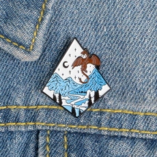 Enamel dragon brooch with snow mountains pinned on a denim jacket collar close-up
