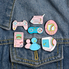 Detail of retro video game enamel pins on denim jacket showing console and controller