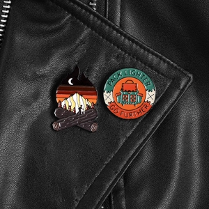 Outdoor enamel pins with campfire and backpack pinned on a black leather jacket lapel