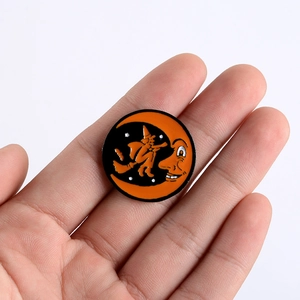 Halloween enamel pin badge with orange moon face and flying witch silhouette on black