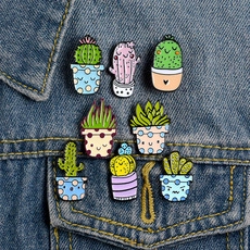 Detailed set of eight cartoon cactus alloy pins on blue denim fabric background