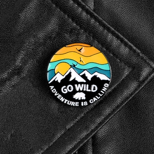 Detail of enameled mountain brooch on leather with Go Wild Adventure Is Calling text