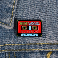 Gros plan sur un pin's émaillé vintage en forme de cassette des années 90 sur denim