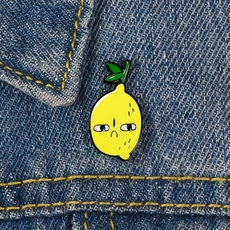 Gros plan détaillé d'un pin's citron jaune en émail sur un tissu en jean bleu