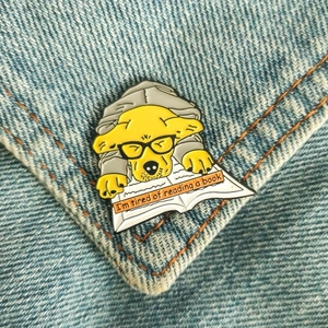 Détail du pin's chien fatigué sur denim avec texte sur la lecture des livres