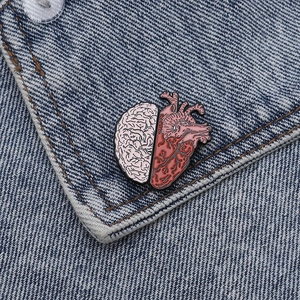 Close-up of brain and heart enamel pin on denim jacket showing creative design details