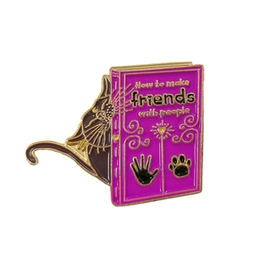 Détail d'une épingle en émail violette avec chat noir et lettrage doré élégant
