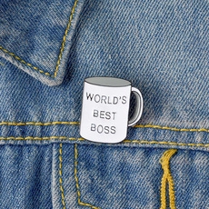 Détail d'un pin's émaillé tasse de café World's Best Boss sur du tissu en jean
