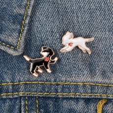 Détail de pins émaillés chats noir et blanc avec feuille d'érable sur veste en jean