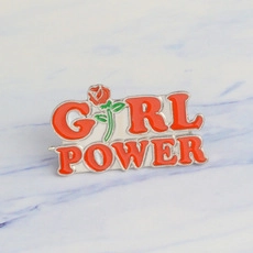 Macro detail of the red Girl Power enamel pin featuring a rose pattern on metal