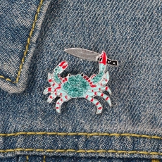 Détail d'un pin's en émail crabe bleu avec couteau sur une veste en jean