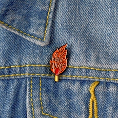 Detail of creative match flame enamel pin with engraving on a blue denim jacket pocket