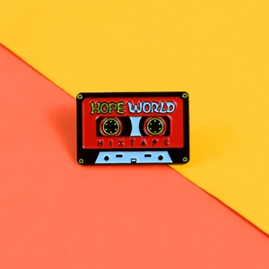 Détail de la broche émaillée rétro en forme de cassette avec texte Hope World gravé