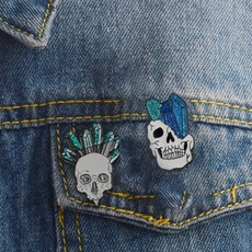 Detail of gothic enamel skull brooches with green and blue crystals on denim jacket