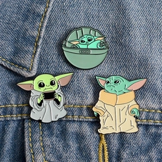 Detail view of three Grogu enamel pins set against a dark blue denim fabric texture