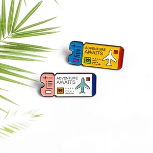 Detail of travel boarding pass enamel pins with Adventure Awaits text and palm leaf background