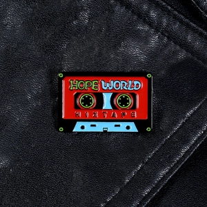 Macro d'un pin's émaillé vintage en forme de cassette avec texte Hope World sur cuir