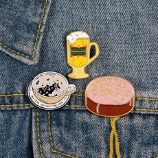 Detail of magic movie enamel pins featuring butter beer, potion cup, and cake on denim