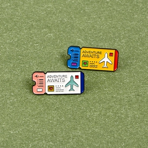 Detailed macro view of colorful enamel airplane ticket pins with Adventure Awaits engraving