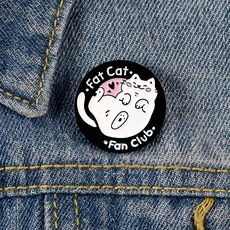 Detail of a round Fat Cat Fan Club pin badge on blue denim fabric background