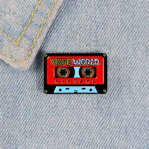 Gros plan du pin's émaillé cassette rétro avec texte Hope World sur denim