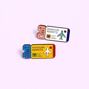 Detailed close-up of colorful enamel boarding pass pins with Adventure Awaits engraving