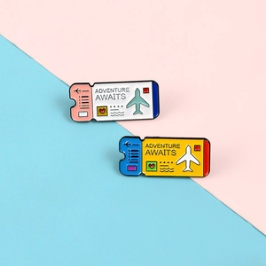 Macro shot of two enamel boarding pass pins with Adventure Awaits text on colorful background