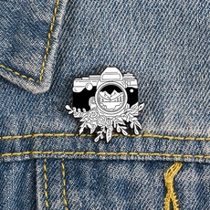 Détail d'une épinglette en émail d'appareil photo rétro avec lentille de montagne sur denim