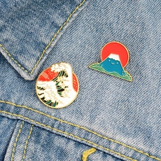 Detail view of Great Wave off Kanagawa and smiling Mount Fuji enamel pins on a denim jacket