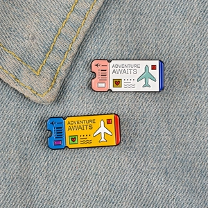 Creative airplane ticket enamel pins on denim with Adventure Awaits theme