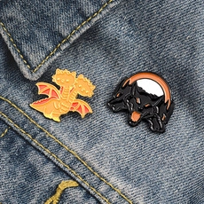 Detailed view of mythical three-headed dragon and Cerberus enamel pins on blue denim fabric