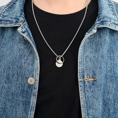 Gros plan sur le collier pendentif double cercle argenté porté sur une veste en jean