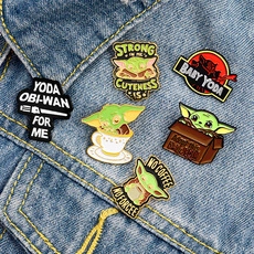 Detailed close-up of six Baby Yoda enamel pins displayed on blue denim fabric background