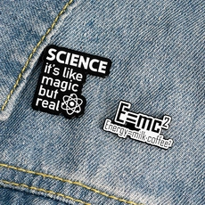 Détail de broches en émail sur le thème de la science avec formule E=mc² sur denim