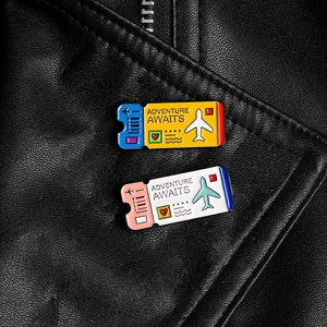 Creative airplane ticket enamel pins with Adventure Awaits text on leather jacket