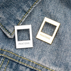 Macro detail of Pantone style blue cat planet enamel pins on denim fabric background